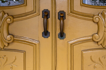 Two exterior vintage doors of a house with metal door knobs. The wooden decorative doors are...