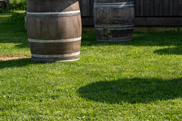 Multiple aged wooden whisky barrels outside on lush green grass.  The oak wine barrels are used for...