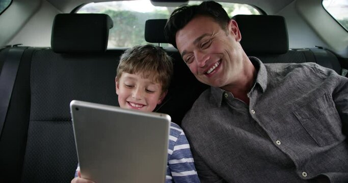 Smile, dad and child in car with tablet, watching video or online games on road trip together. Travel, digital app and father with boy on backseat of taxi, internet and transport, laughing on journey