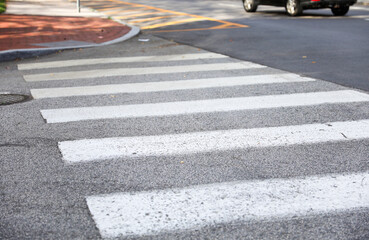 crosswalk on urban street, painted white lines symbolize safety and community, pedestrians crossing, city life, traffic, pedestrian-friendly environment, road safety, walking, urban infrastructure
