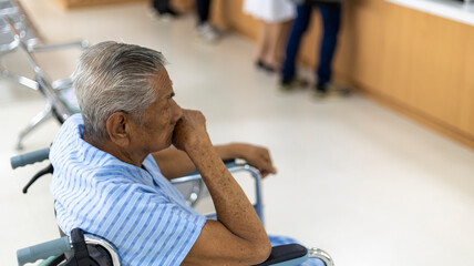 Elderly male patient waiting to see doctor with worry putting hand on his head.