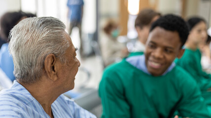 Old man patient talking with a young African doctor waiting to get health medical check up at a...