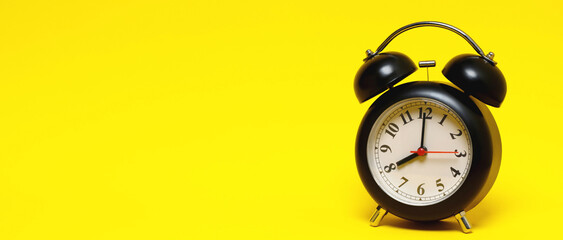 vintage retro alarm clock eight minutes to twelve time o'clock on  yellow background.