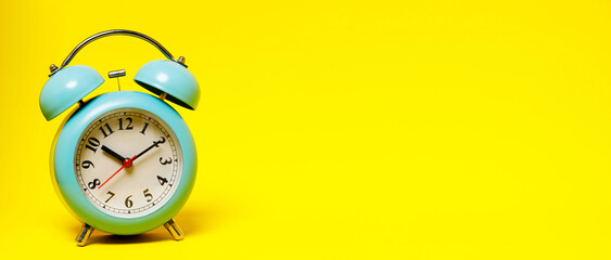vintage retro alarm clock Four o'clock, ten minutes on yellow background.