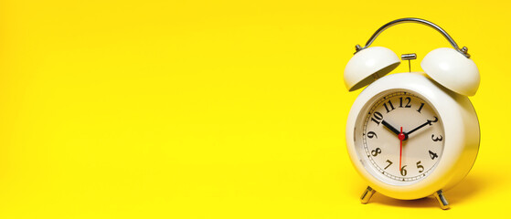 vintage retro alarm clock Four o'clock, ten minutes on yellow background.