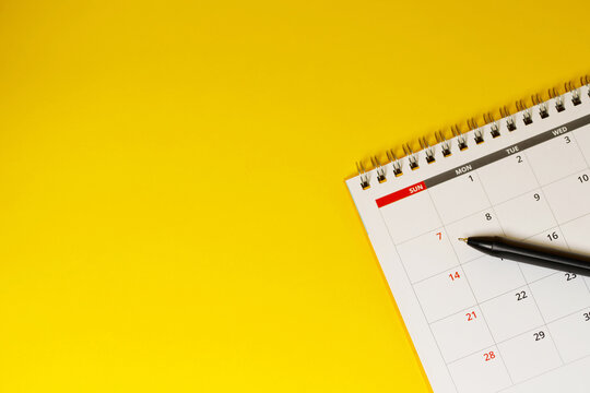 calendar month schedule to make appointment meeting or manage timetable each day lay and pen on yellow background for planning work and travel concept.