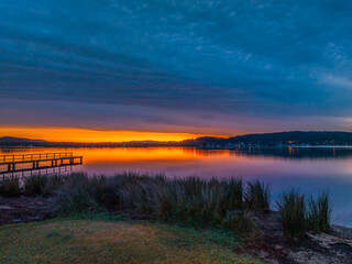 Heavy cloud covered sunrise over the bay with colour and reflections