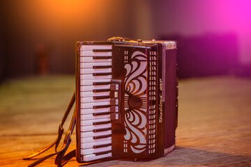 Old accordion on rustic wooden surface with dark background and Low key lighting, selective focus.