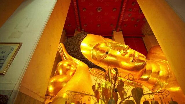 Beautiful golden Buddha head in a reclining position at Wat Phra Non Chak Si Worawihan Sing Buri Thailand..Golden Buddha The beautiful reclining posture in the pavilion is worshiped by the people.