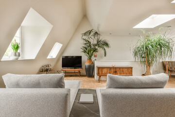 a living room with two couches and a flat screen tv in the corner of the room is decorated with potted plants