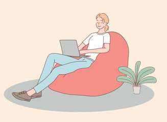 woman working with laptop and sitting on beanbag with houseplant beside