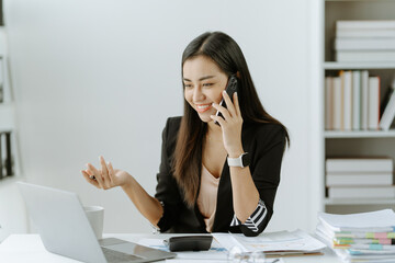Asian woman sitting at a desk working in the office use a computer, laptop
