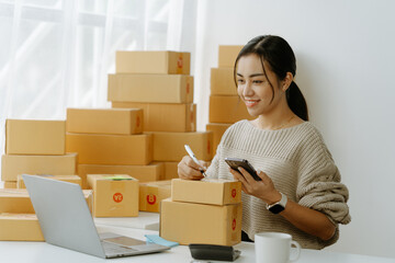 ortrait of a small business startup, SME owner, female entrepreneur, working, unboxing, checking orders online. To prepare to pack boxes for sale to SME customers online business ideas