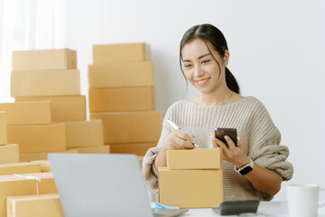 ortrait of a small business startup, SME owner, female entrepreneur, working, unboxing, checking orders online. To prepare to pack boxes for sale to SME customers online business ideas