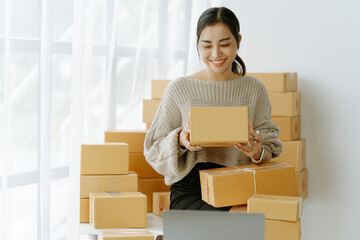 ortrait of a small business startup, SME owner, female entrepreneur, working, unboxing, checking orders online. To prepare to pack boxes for sale to SME customers online business ideas