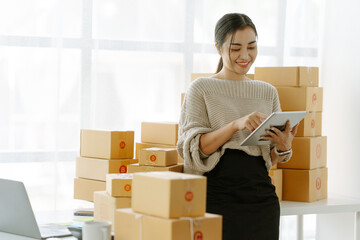 ortrait of a small business startup, SME owner, female entrepreneur, working, unboxing, checking orders online. To prepare to pack boxes for sale to SME customers online business ideas