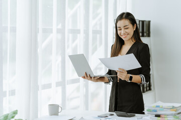 Asian woman sitting at a desk working in the office use a computer, laptop