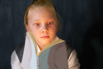 Surprise, reading and child student with a book in the classroom for education, learning or...