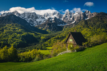 Cute small hut on the slope and snowy mountains, Slovenia