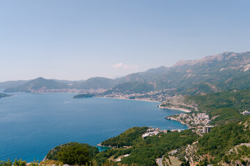 Fototapeta na wymiar Bay of Kotor surrounded by green mountains in a light haze against the blue sky. Montenegro