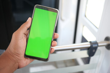 young man hand using smart phone with green screen inside of metro train