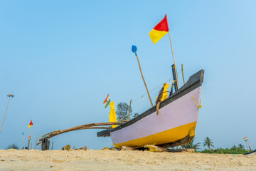 old fishing boats in the sand on the ocean in India on blue sky background - obrazy, fototapety, plakaty