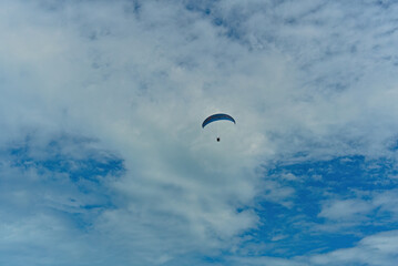 Floating paraglider in the sky with clouds in the mountains