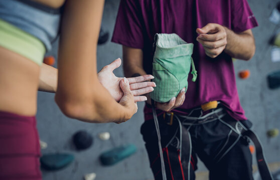 A couple of climbers use talc befor climbing an artificial wall with colorful grips and ropes.