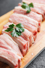 Fresh meat pork ribs with green on wooden board, top view on dark background