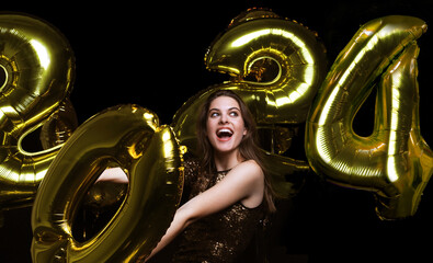 Happy gorgeous girl in stylish sexy party dress holding gold 2021 balloons, having fun at New...