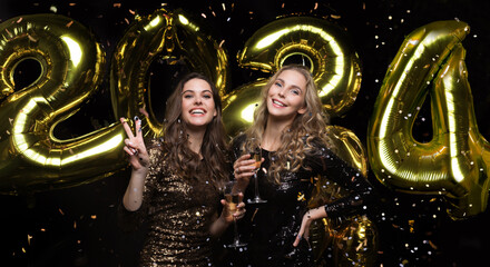 Two young ladies drinking champagne. Image of girls with balloons isolated on black background,...