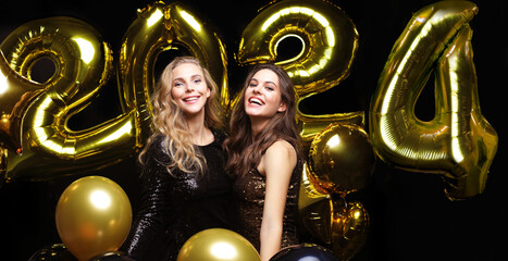 Happy gorgeous girls in stylish sexy party dresses holding gold 2021 balloons, having fun at New Year's Eve Party.