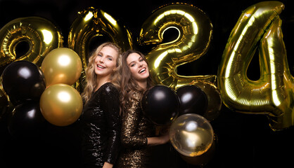 Happy gorgeous girls in stylish sexy party dresses holding gold 2021 balloons, having fun at New...