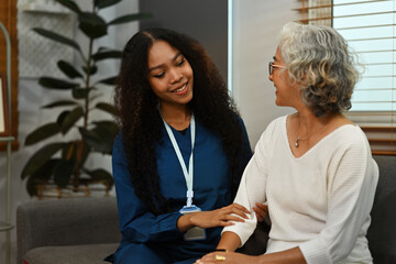An African nurse holding a Senior patient's hands in a nursing home for healthcare, empathy, and support in health condition, and psychology. Medical advice and counseling, therapy