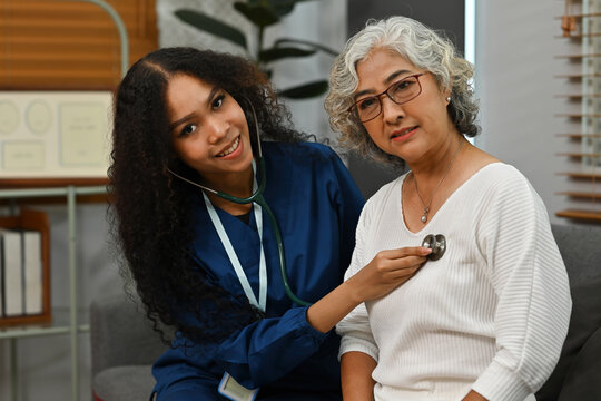 An African doctor using a stethoscope to listen to the respiration or heartbeat of an old patient woman. annual health check, Elderly people and nursing home concepts
