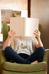 Person cover face with books in library, bookstore or shop for research, learning and relax on sofa. Literature, knowledge and customer with book for education, information and reading for hobby