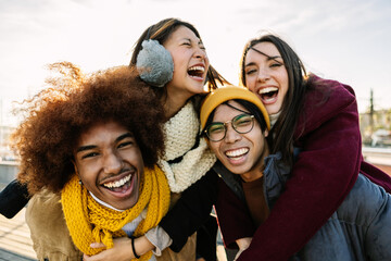 Young group of friends hanging out enjoying city break on winter vacation. Happy millennial diverse people laughing, social gathering in city street. Friendship and youth community concept. - obrazy, fototapety, plakaty