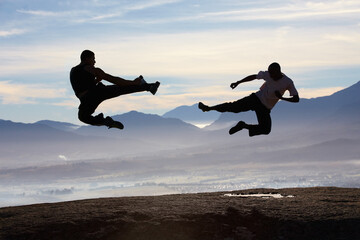 Flying, kick and karate men on mountain top for fitness, training or body, speed or power on sky background. Martial arts, taekwondo or MMA friends in nature with jump, fighting or sports exercise - obrazy, fototapety, plakaty