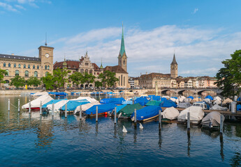 Zurich, Switzerland. Cityscape with Fraumunster church and pier with boats on the Limmat River.