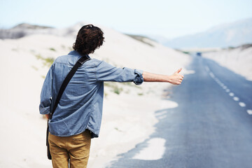 Back, man or hitchhiker in nature on road for travel, destination or road trip with thumbs up in street. Rear View, person or hand gesture outdoor or hitchhiking, transportation and waiting in summer