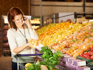 Woman, talking and smartphone with vegetable shopping for healthy food, supermarket and communication. Happy, person and call on cellphone at grocery retail, fruit and wellness store for nutrition