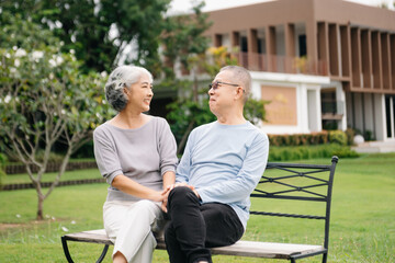 Fototapeta premium Asian senior couple having a good time. They laughing and smiling while sitting outdoor in park. Lovely senior couple.