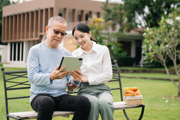 Fototapeta premium Happy adult granddaughter and senior grandfather having fun enjoying talk while relaxing sitting outdoor in park..