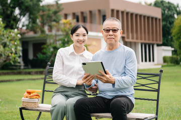 Fototapeta premium Happy adult granddaughter and senior grandfather having fun enjoying talk while relaxing sitting outdoor in park..