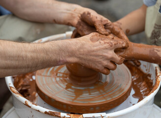 The potter teaches a young student.