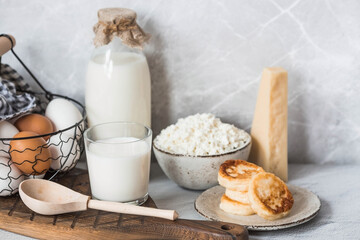 Fresh dairy products, milk, cottage cheese, cheesecakes, eggs in stylish ceramic dishes on a gray background. The concept of natural, dietary nutrition. Useful products.