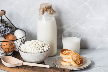 Fresh dairy products, milk, cottage cheese, cheesecakes, eggs in stylish ceramic dishes on a gray background. The concept of natural, dietary nutrition. Useful products.