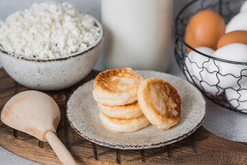 Fresh dairy products, milk, cottage cheese, cheesecakes, eggs in stylish ceramic dishes on a gray background. The concept of natural, dietary nutrition. Useful products.