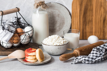 Fresh dairy products, milk, cottage cheese, cheesecakes, eggs in stylish ceramic dishes on a gray background. The concept of natural, dietary nutrition. Useful products.