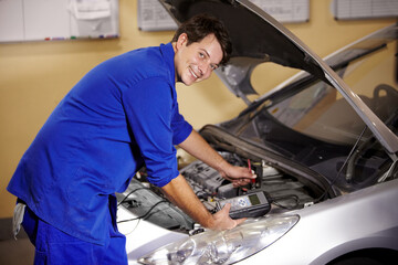 Portrait, car and repair with a mechanic man in a workshop as an engineer looking at the engine of a vehicle. Garage, service or quote with a young technician working under the hood of an automobile